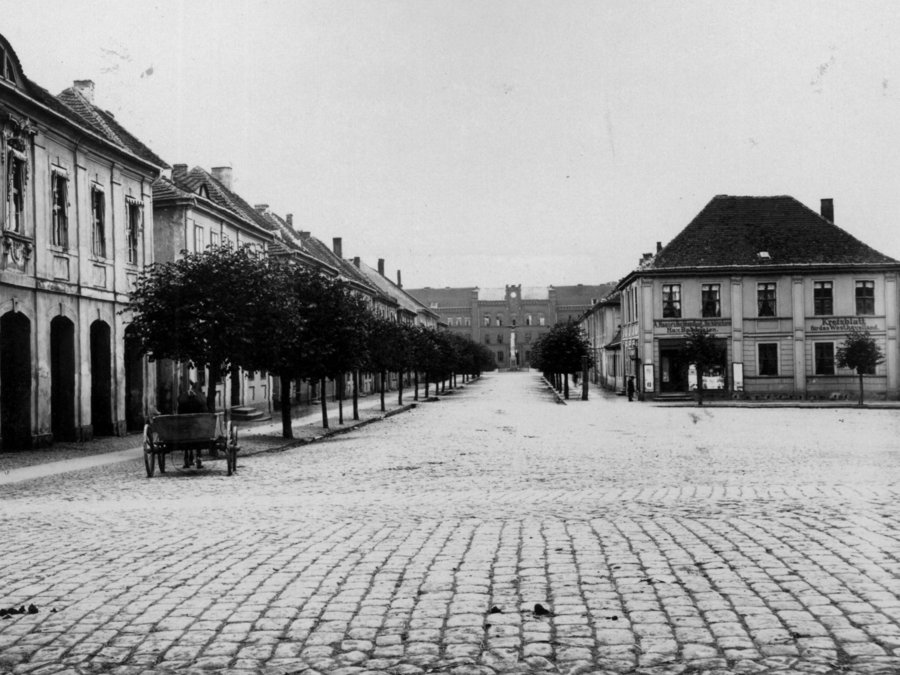 Ansicht des heutigen Schlesuenplatzes um 1900. Am damaligen Paradeplatz befanden sich links das Neustädtische Rathaus, im Hintergrund das Prorealgymnasium und rechts die Buchdruckerei von Max Babenzien. Aufnahme um 1900 von Hermann Ventzke. 