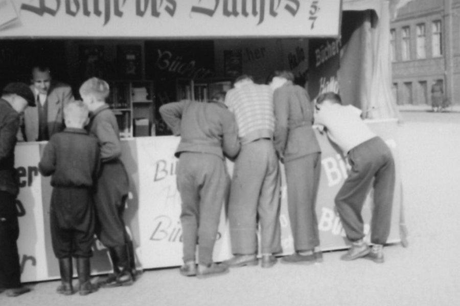 Woche des Buches an der Berliner Straße 1957. Junge Männer umringen den Stand
